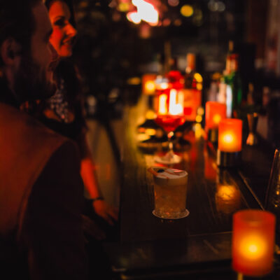 Intimate moment as couple receives cocktails in softly lit bar